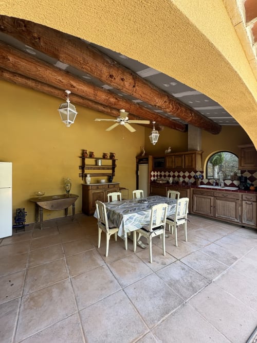 Salle à manger à la Conciergerie Maurin à Arles avec murs jaunes, poutres en bois et table dressée pour les clients
