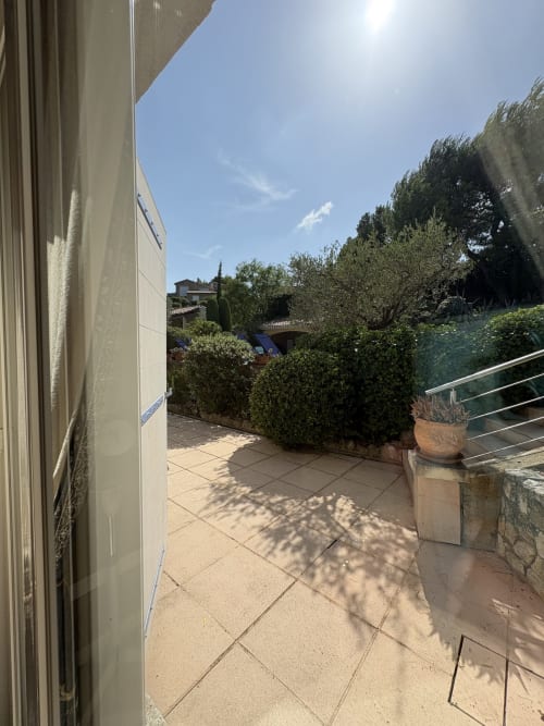 Terrasse ensoleillée de la Conciergerie Maurin à Arles avec patio carrelé, plantes en pot et verdure luxuriante