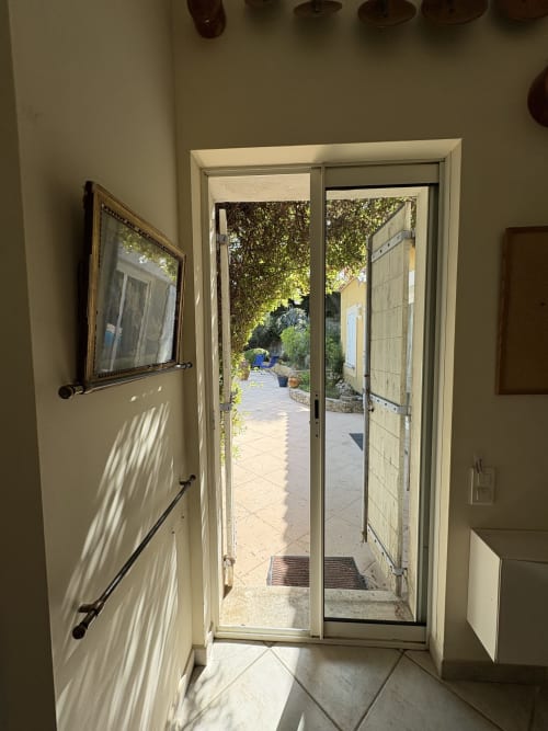 Portes vitrées ouvertes sur le jardin-patio ensoleillé de l'hôtel Conciergerie Maurin à Arles, France