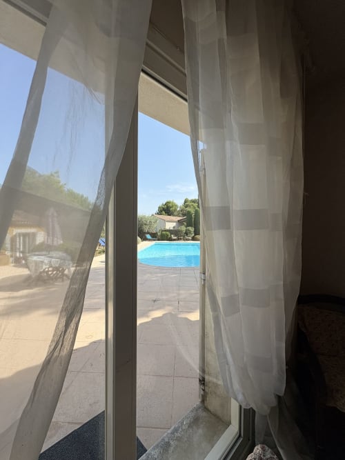 Vue depuis la chambre Le Paradis du Paradou à travers les voilages vers la piscine de la Conciergerie Maurin à Arles, France