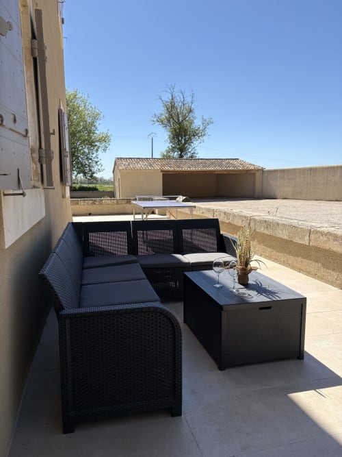 Espace de détente extérieur au Mas en Camargue, Arles avec canapé en rotin noir, table, ping-pong et cour rurale