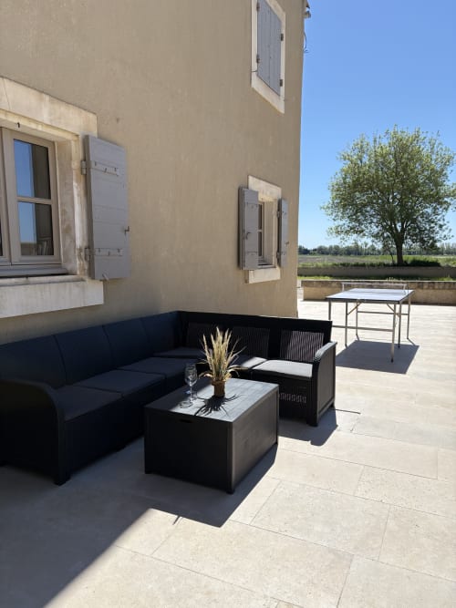 Terrasse extérieure du Mas en Camargue à Arles avec mobilier noir, ping-pong et vue sur la campagne rurale