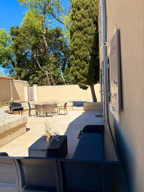 Terrasse ensoleillée au Mas en Camargue, Arles avec mobilier extérieur, murs en pierre et arbres méditerranéens