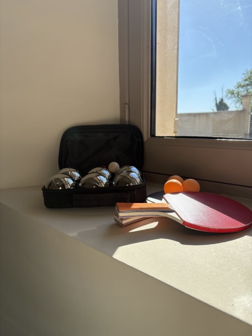 Raquettes et balles de ping-pong dans une chambre ensoleillée de l'hôtel Mas en Camargue, Arles, avec vue sur la fenêtre