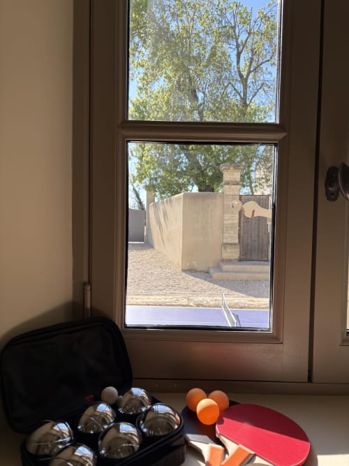 Portes vitrées doubles ouvrant sur cour avec boules de pétanque et jeux en plein air à la Conciergerie Maurin, Arles