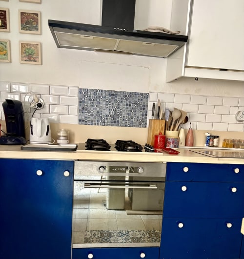 Cuisine moderne avec armoires bleues, dosseret en carrelage blanc et électroménagers en acier inoxydable dans un appartement à Arles