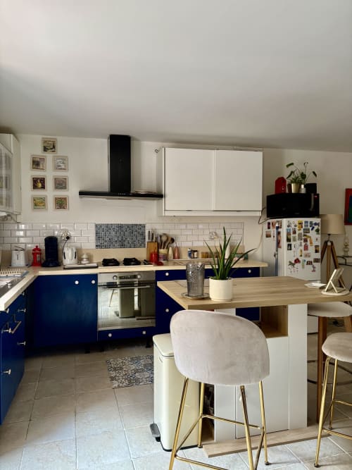Cuisine moderne avec armoires bleu marine, comptoirs blancs et îlot-bar dans un appartement à Arles