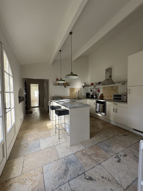 Cuisine contemporaine avec îlot de repas et luminaires suspendus au Gîte château de Pannis, Arles