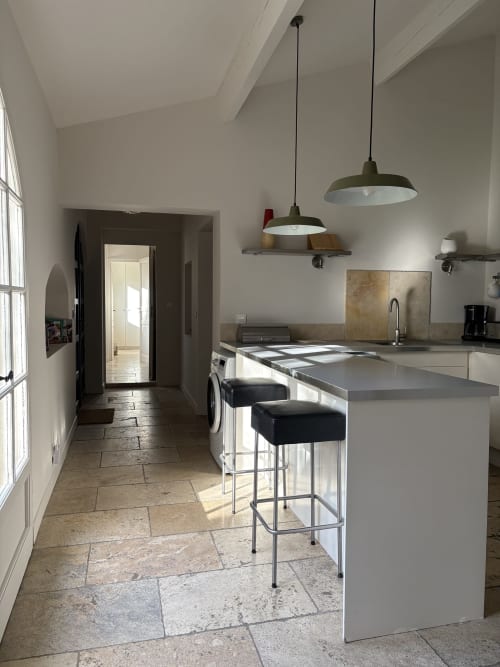 Cuisine moderne avec îlot de cuisine, luminaires suspendus et sol en pierre au Gîte Château de Pannis, Arles
