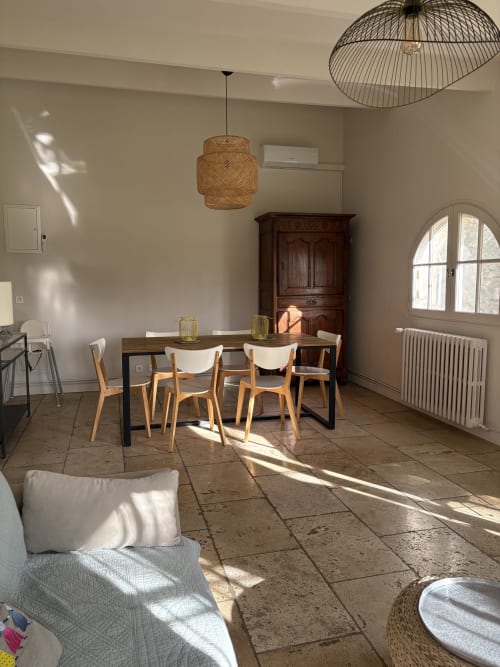 Salle à manger lumineuse au Gîte Château de Pannis, Arles avec chaises en bois, luminaire suspendu tissé, carrelage en terre cuite