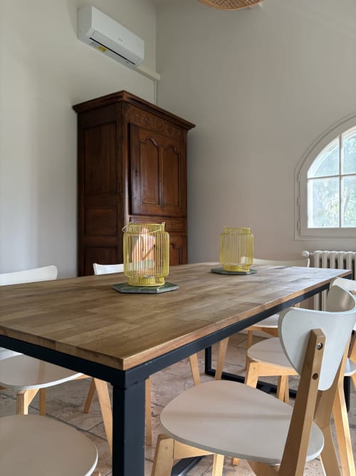 Salle à manger du Gîte Château de Pannis à Arles avec table en bois, chaises modernes et lanternes jaunes