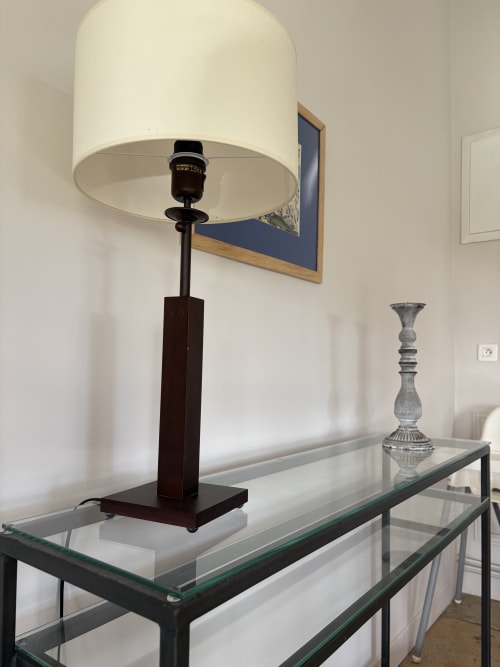 Lampe de table moderne à abat-jour cylindrique crème et base en bois foncé sur console en verre, Gîte château de Pannis, Arles.