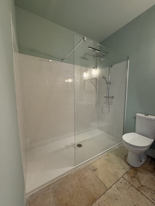 Salle de bain moderne au Gîte Château de Pannis, Arles avec douche vitrée, carrelage blanc métro, toilettes et travertin
