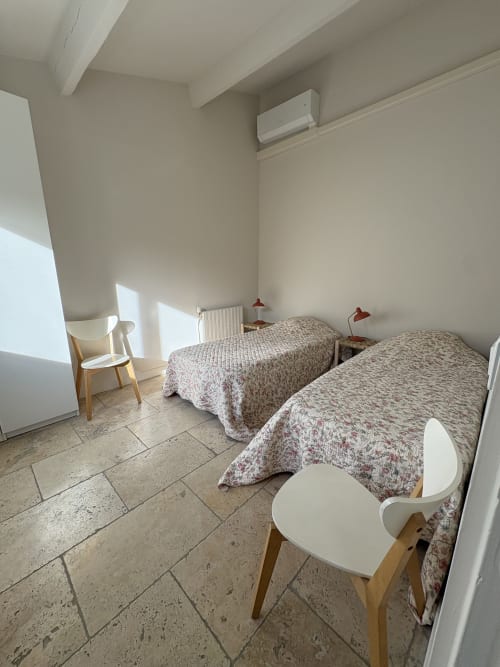 Deux lits jumeaux aux courtepointes motifs dans la chambre lumineuse du Gîte Pannis à Arles, avec carrelage et climatisation
