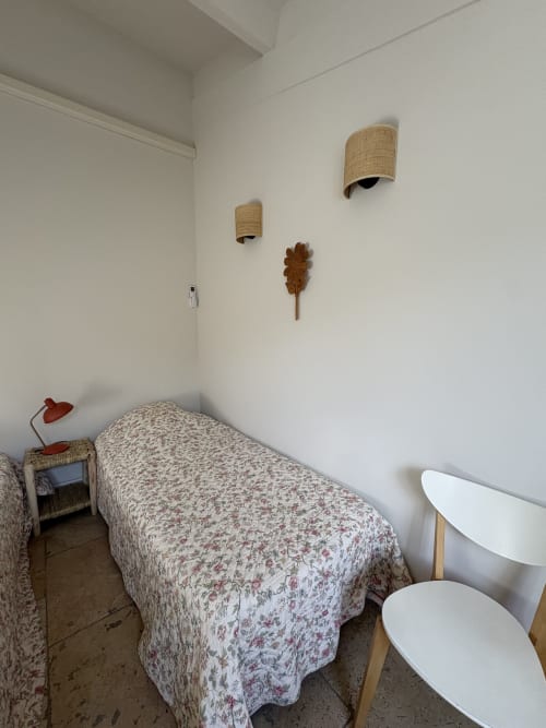 Chambre épurée au Gîte château de Pannis, Arles, avec lit simple, appliques murales tressées et touches de bois
