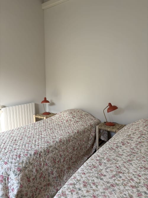 Lits jumeaux avec courtepointes à motifs floraux et lampes de lecture rouges dans la chambre du Gîte château de Pannis, Arles