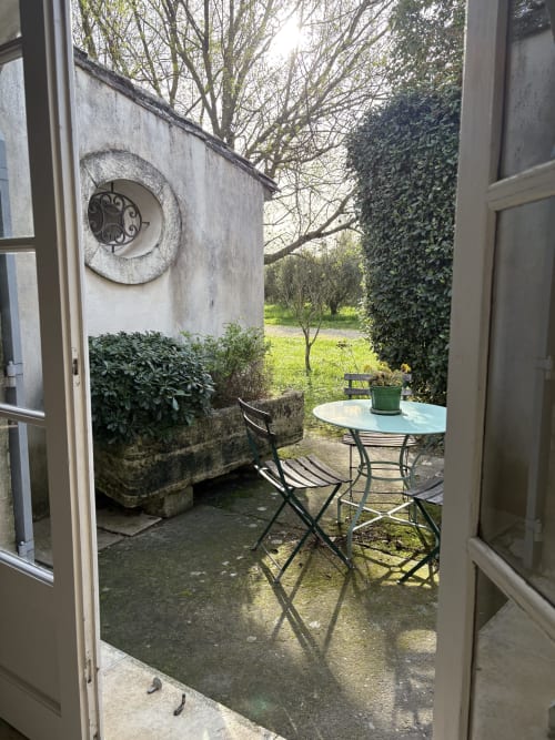 Espace de détente extérieur du Gîte château de Pannis à Arles avec table ronde, chaises, plante en pot et vue sur le jardin