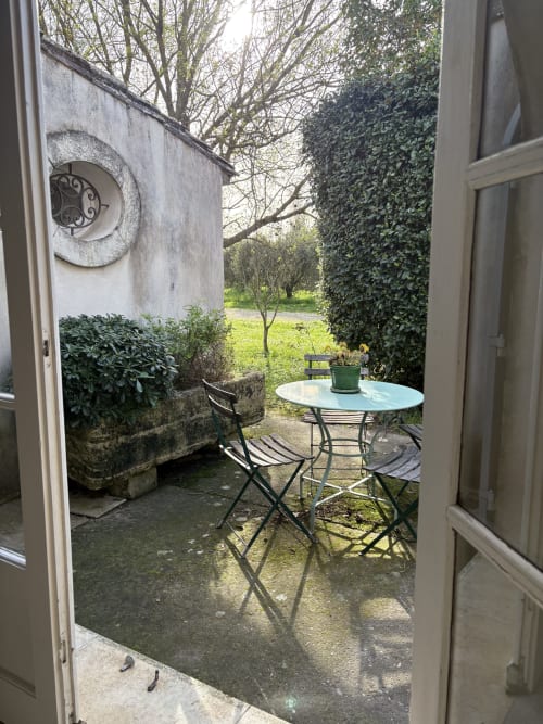 Terrasse avec vue sur le jardin du Gîte château de Pannis à Arles, table ronde, chaises et murs couverts de lierre