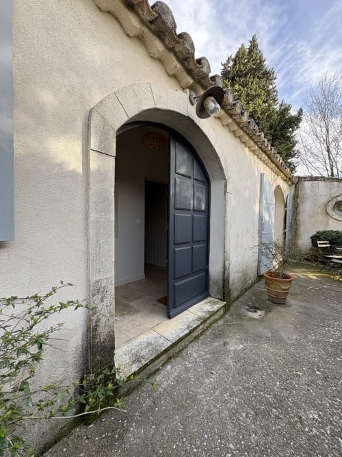 Entrée en pierre avec porte voûtée bleu foncé au Gite Chateau de Pannis à Arles, France, donnant sur cour jardin