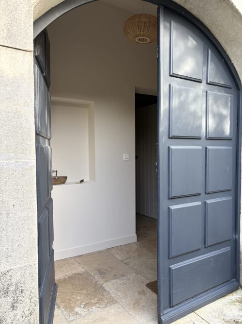Portes bleues arquées en bois s'ouvrant sur l'entrée lumineuse du Gîte château de Pannis à Arles, France
