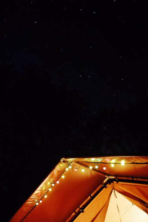 Tente illuminée avec guirlandes lumineuses chaleureuses sous un ciel étoilé aux gîtes de Cormenin