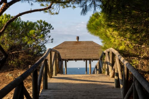 Pasarela de madera con barandillas hacia el pabellón frente al mar en Hostal La Moyareja en Rota, España, rodeado de costa
