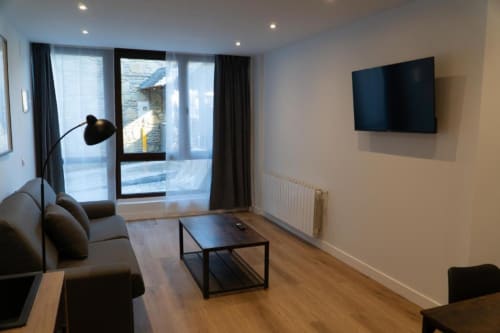 Modern hotel suite at La Borda del Gato Rafa in Vielha with wall-mounted TV, sofa, and mountain views