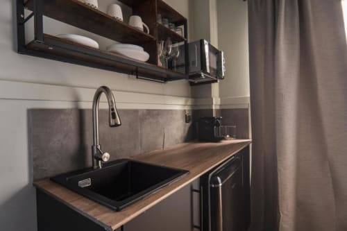 Modern kitchenette at La Borda del Gato Rafa in Vielha with black sink, wood countertop, and wall shelving