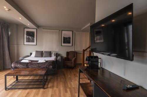 Modern hotel suite at La Borda del Gato Rafa in Vielha with bed, TV, sitting area and wooden floors
