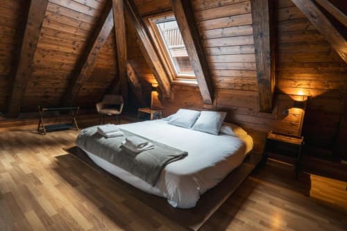 Cozy attic bedroom at La Borda del Gato Rafa in Vielha with wooden beams, skylight, and white bedding