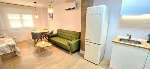Moderno estudio en Murcia con sofá verde, nevera vintage, comedor y cocina integrada