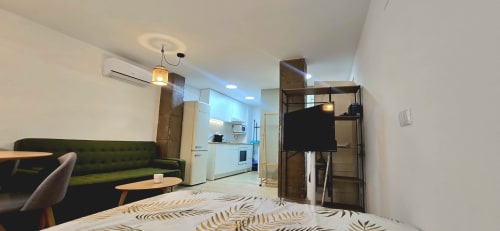 Acogedor estudio en el centro de Murcia con sofá verde, cocina americana y comodidades modernas