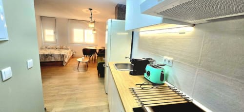 Cocina y sala de estar modernas en estudio amueblado de Murcia con cocineta equipada, comedor y vista al dormitorio