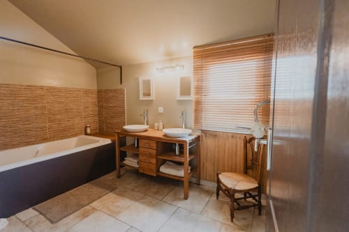 Salle de bain spacieuse aux Les gîtes de Cormenin avec double vasque, baignoire îlot et vue sur le jardin à Saint-Hilaire-sur-Puiseaux