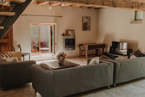 Spacieux séjour de la villa aux Gîtes de Cormenin avec canapé gris, cheminée et portes donnant sur le jardin