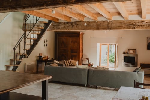 Séjour ouvert des Gîtes de Cormenin avec poutres apparentes, canapé gris et portes donnant sur le jardin