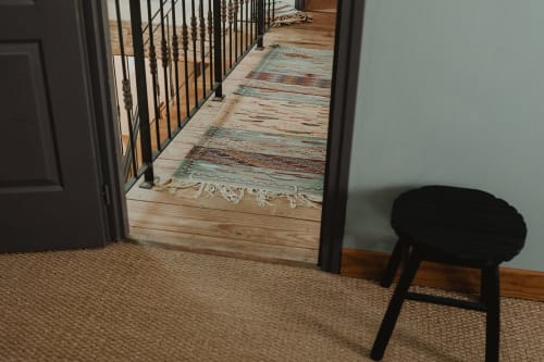 Couloir de la villa Les gîtes de Cormenin avec tapis rayé, rampe noire et parquet