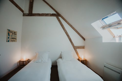 Deux lits jumeaux dans la chambre moderne de la villa aux Gîtes de Cormenin, Saint-Hilaire-sur-Puiseaux, avec poutres apparentes et vue sur le jardin