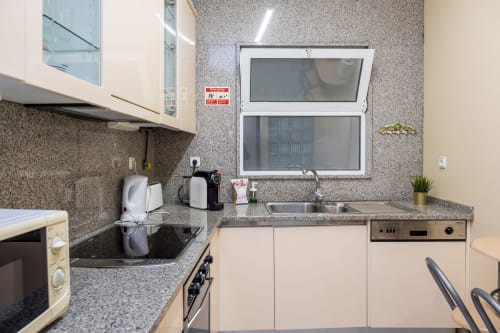 Cozinha moderna nos RH Charming Apartments Braga com bancadas de granito, armários creme e vistas para as janelas