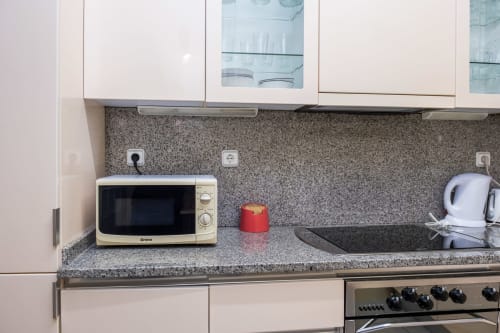 Bancada moderna em RH Charming Apartments Braga com micro-ondas, chaleira e backsplash de granito cinza