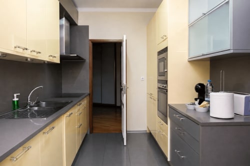 Cozinha tipo galera moderna no RH Charming Apartments em Braga com armários creme, bancadas escuras e aço inoxidável
