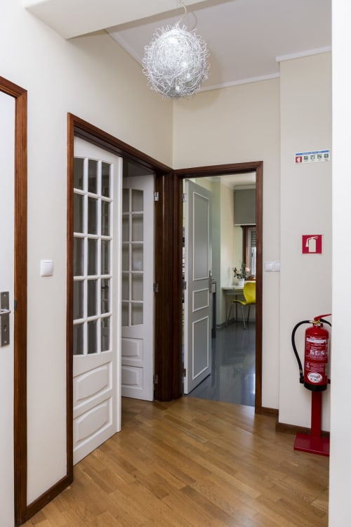 Corredor moderno no RH Charming Apartments em Braga com portas de madeira, luminária pendente e extintor