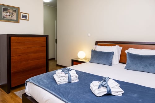 Quarto moderno no RH Charming Apartments em Braga com camas de solteiro, móveis de madeira e roupas de cama limpas