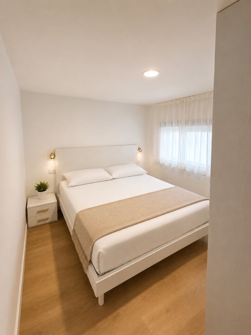 Modernes Studio-Schlafzimmer im Fly High, Morro Jable mit weißem Bett, Nachttisch, eingelassener Beleuchtung und durchscheinenden Vorhängen
