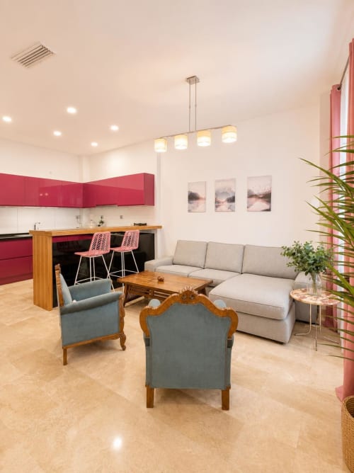 Sala de estar de apartamento moderno de planta abierta con muebles de cocina rojo, sofá gris, mesa de café de madera y estilo contemporáneo