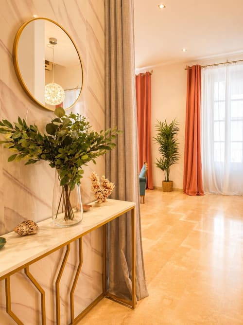 Elegante pasillo del apartamento de Málaga con espejo redondo, flores frescas y suelo de terracota