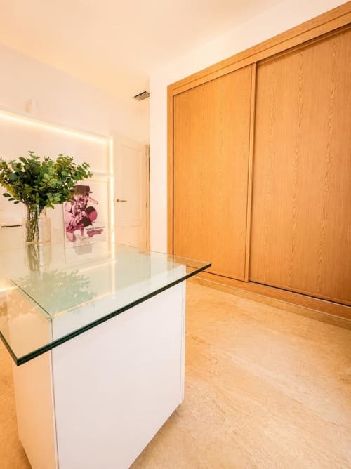 Pasillo moderno de apartamento en Málaga con armario de roble, escritorio de cristal y decoración con planta verde