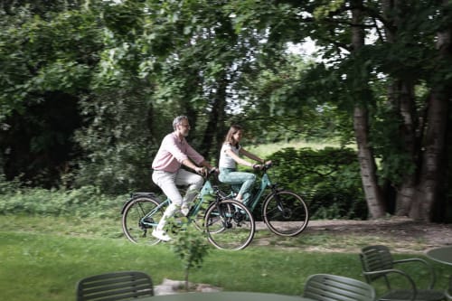 Pareja en bicicleta por el parque verde cerca del Hotel La Prison en Béziers, Francia