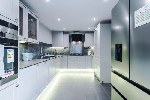 Modern fully equipped kitchen at Vidale Court Manchester villa with white cabinets, black countertops, and stainless steel