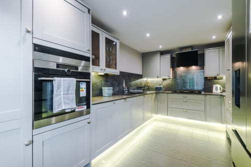Modern fully equipped kitchen in Vidale Court villa, Manchester with white cabinetry, stainless steel appliances and ambient